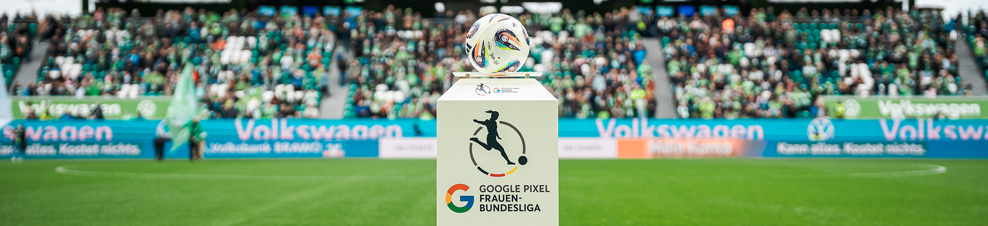 Spielball liegt auf einem Podest mit Logo der Google Pixel Frauen-Bundesliga im Stadion vor Fans.