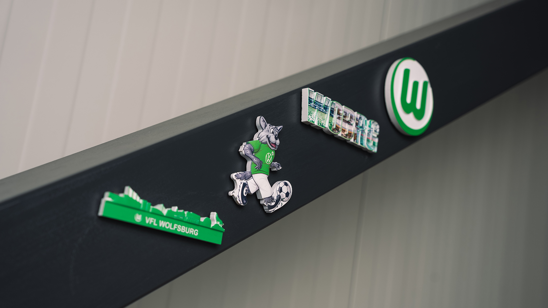 Vier Magneten vom vfL Wolfsburg kleben an einem Metallstab.
