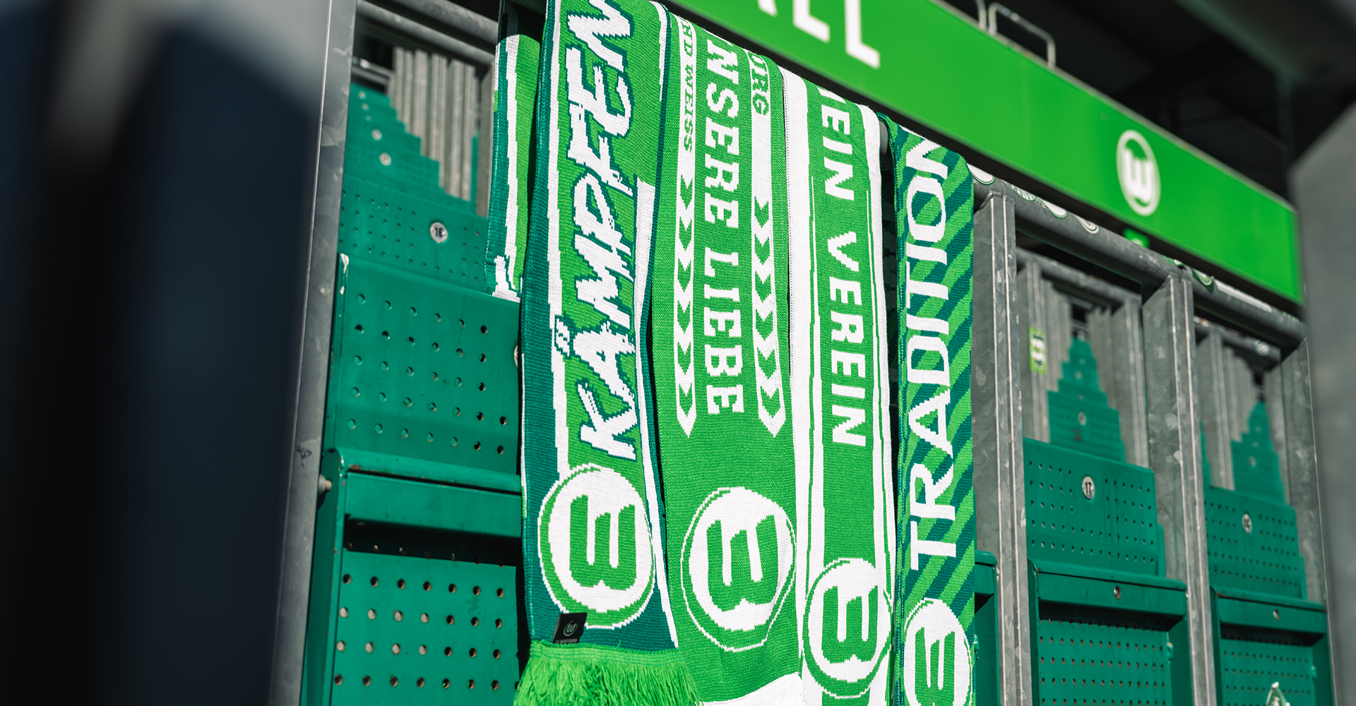 Vier Schals hängen im Stadion über einem Rang im Stehplatzbereich.