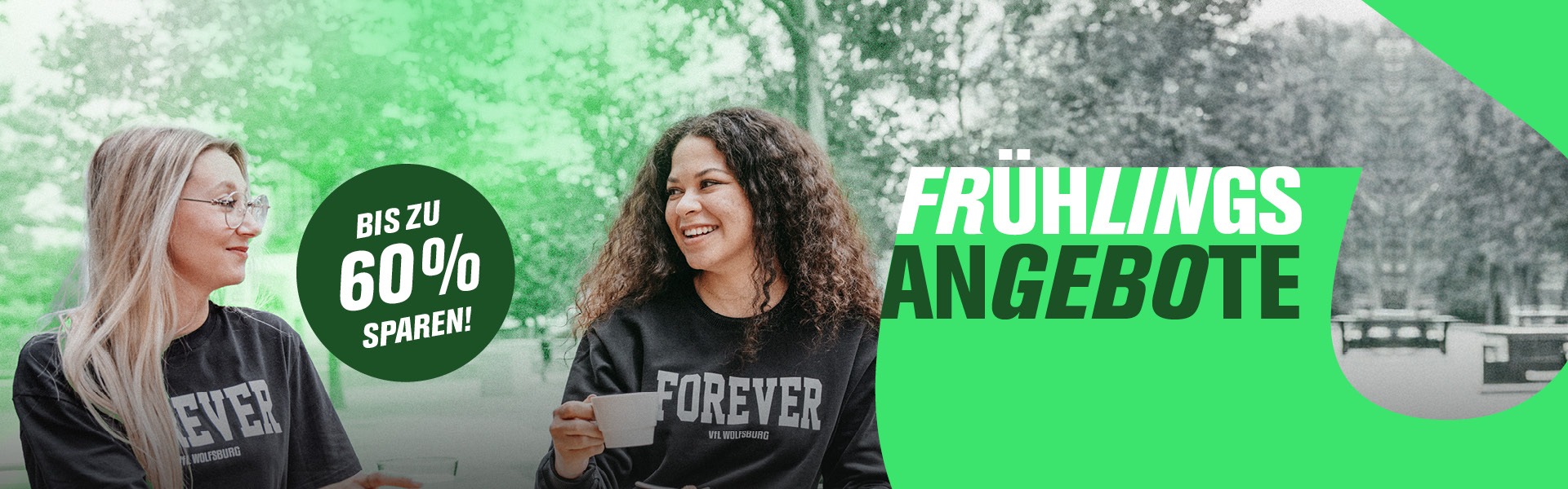Zwei Frauen mit VfL Wolfsburg „Forever“ Fan-Shirts beim Kaffee im Freien.