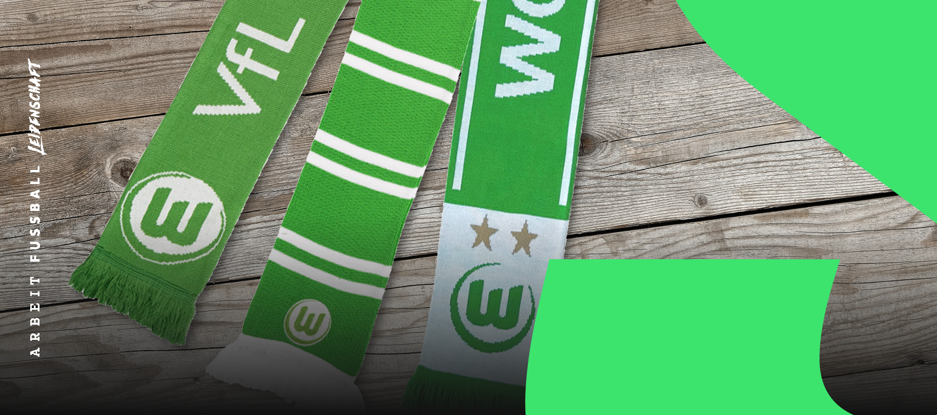 Drei grüne VfL Wolfsburg Fanschals mit Vereinslogo und weißen Streifen liegen auf Holzboden – Fanartikel im klassischen VfL-Design mit „Arbeit. Fußball. Leidenschaft.“ Branding.