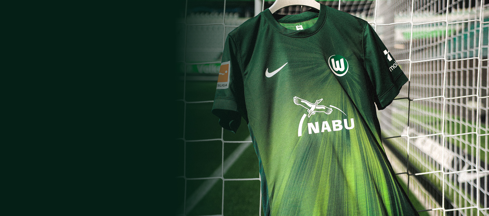 VfL-Wolfsburg-Trikot mit NABU-Schriftzug hängt in einem Tornetz im Stadion.