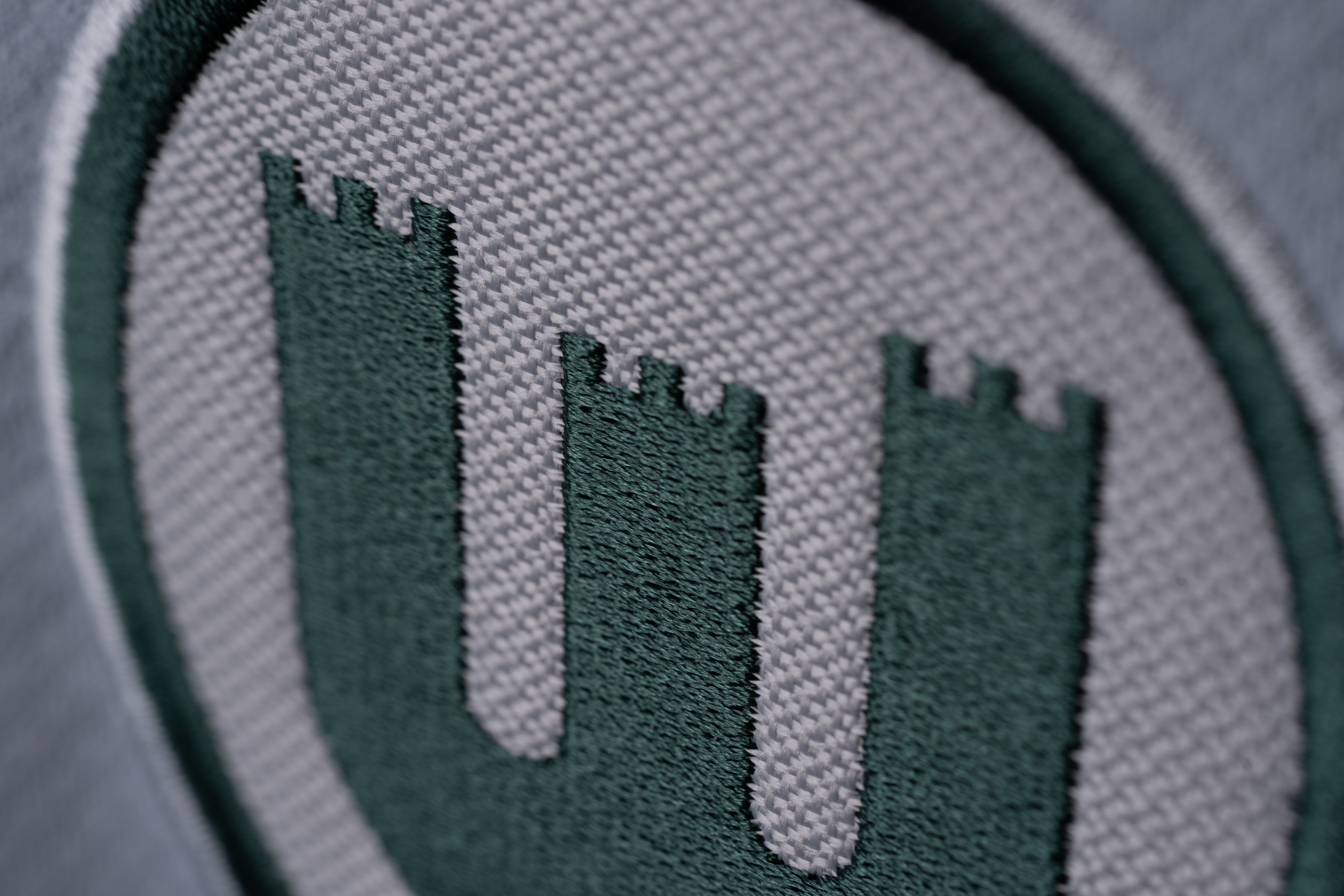 Nahaufnahme eines gestickten VfL-Wolfsburg-Logos auf einem weißen Trikot